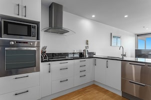 A modern kitchen with stainless steel appliances, white cabinetry, and a wooden floor.