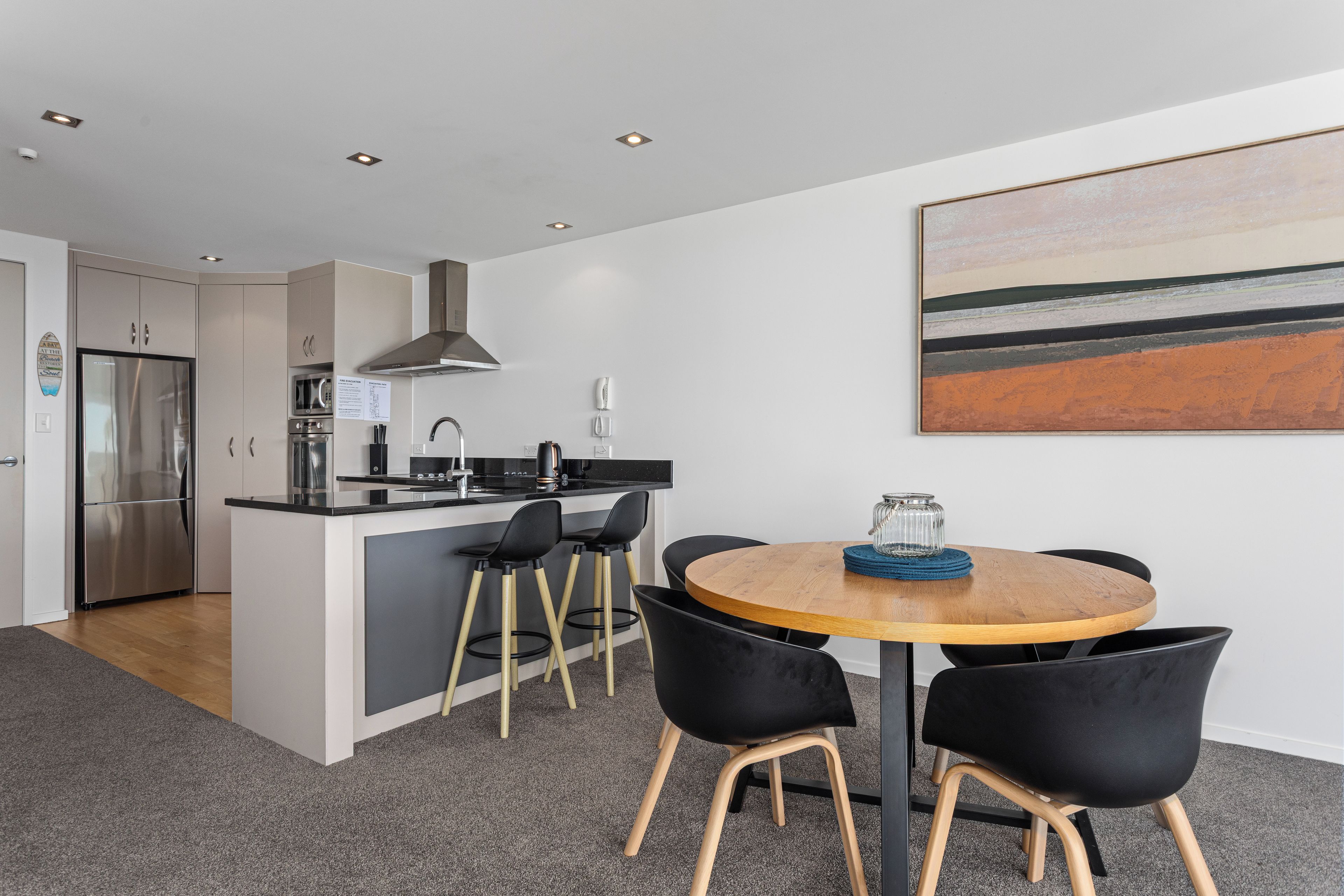 Una cocina moderna con una isla central, taburetes de bar y una mesa de comedor con sillas.