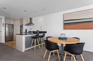 Una cocina moderna con una isla central, taburetes de bar y una mesa de comedor con sillas.