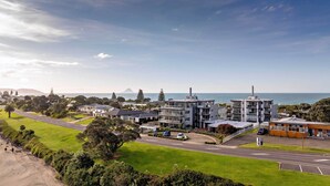 A coastal residential area with modern buildings, a road, and a view of the sea.