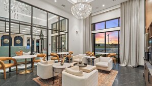 En moderne hotellobby med et siddeområde, store vinduer og en lysekrone.