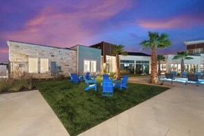 A building with a stone facade, a modern structure with large windows, and outdoor seating with chairs and a pool area. - Cozy 2-bedroom apartment with AC in delightful Round Rock (Round Rock)