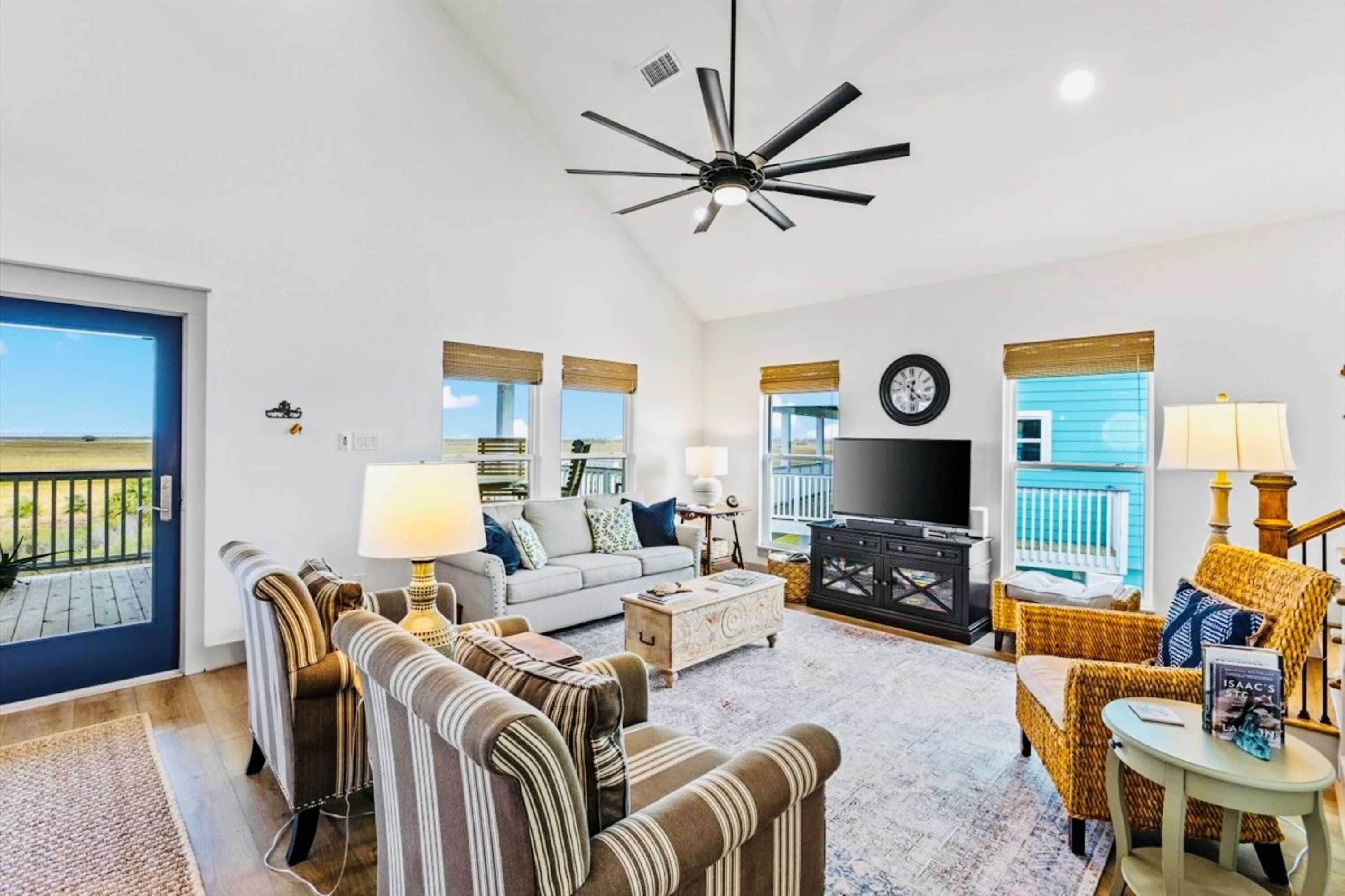 A spacious living room with a ceiling fan, a television, and a view of the outdoors.