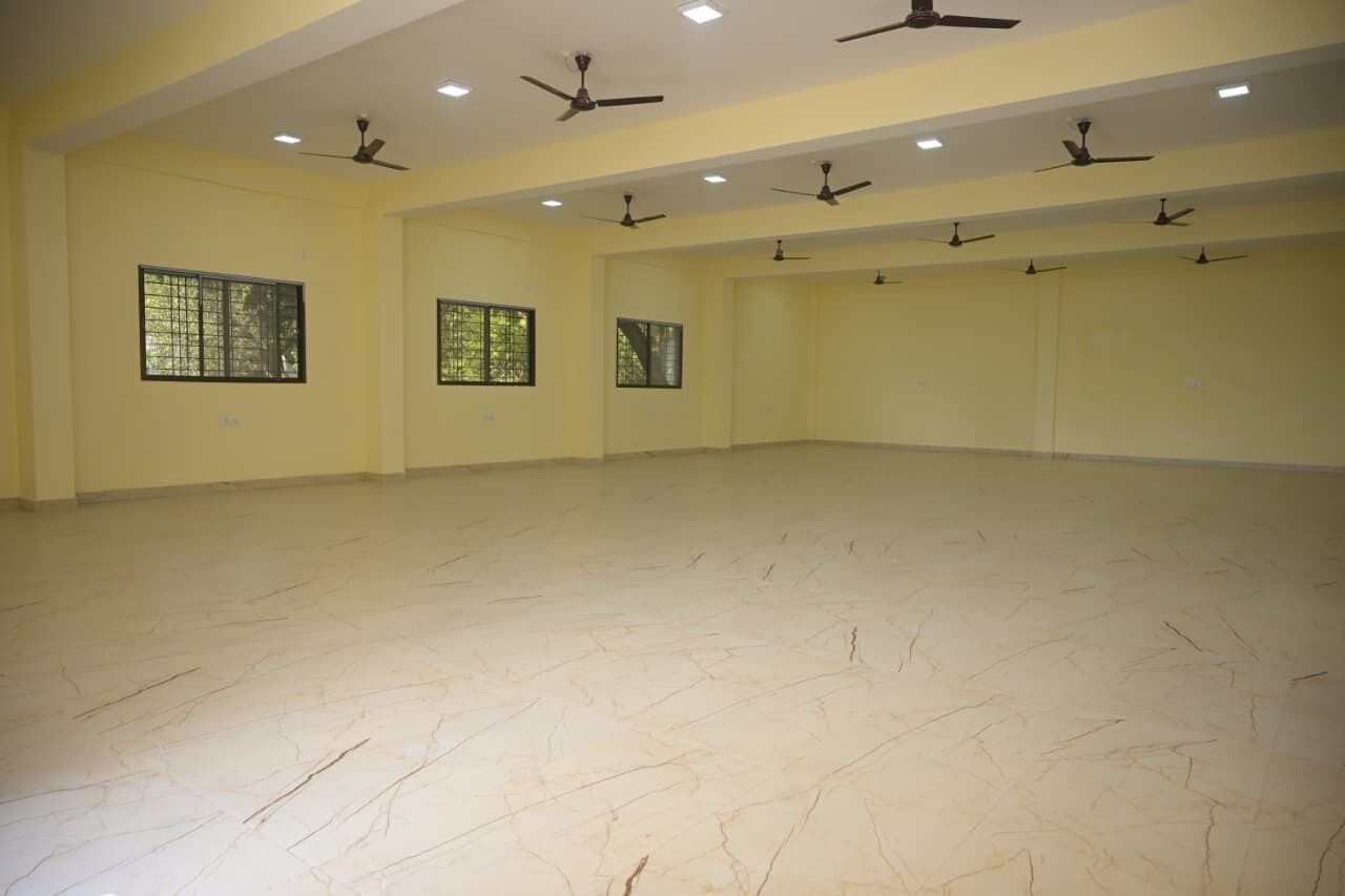 Una habitación amplia con múltiples ventanas, ventiladores de techo y suelo de baldosas.