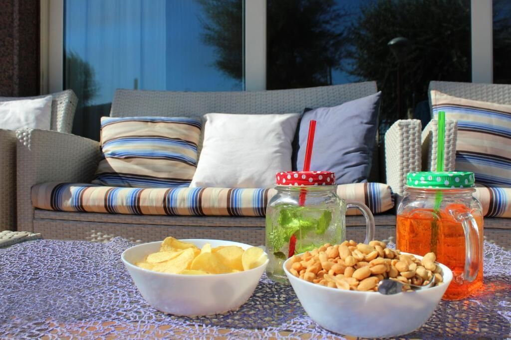 A dining area with a sofa, two bowls of snacks, and two jars of drinks.