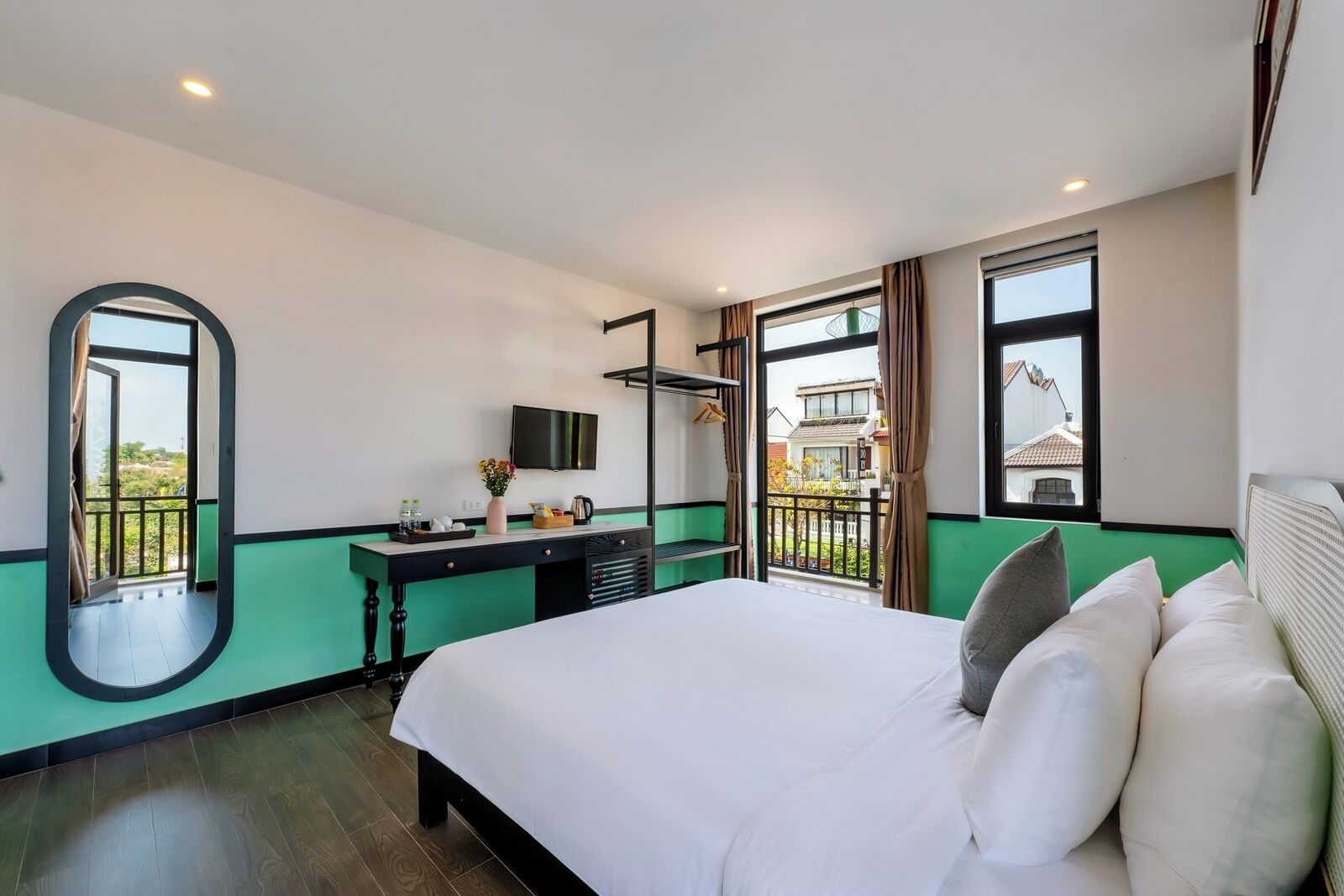 A hotel room with a bed, a desk, a TV, and large windows.