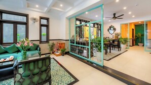 A spacious living area with a sofa, a coffee table, and a dining area with chairs and a table. - Hoi An Ivy Hotel (Da Nang)