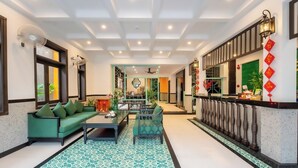 A hotel lobby with a green sofa, a coffee table, and a patterned rug. - Hoi An Ivy Hotel (Da Nang)