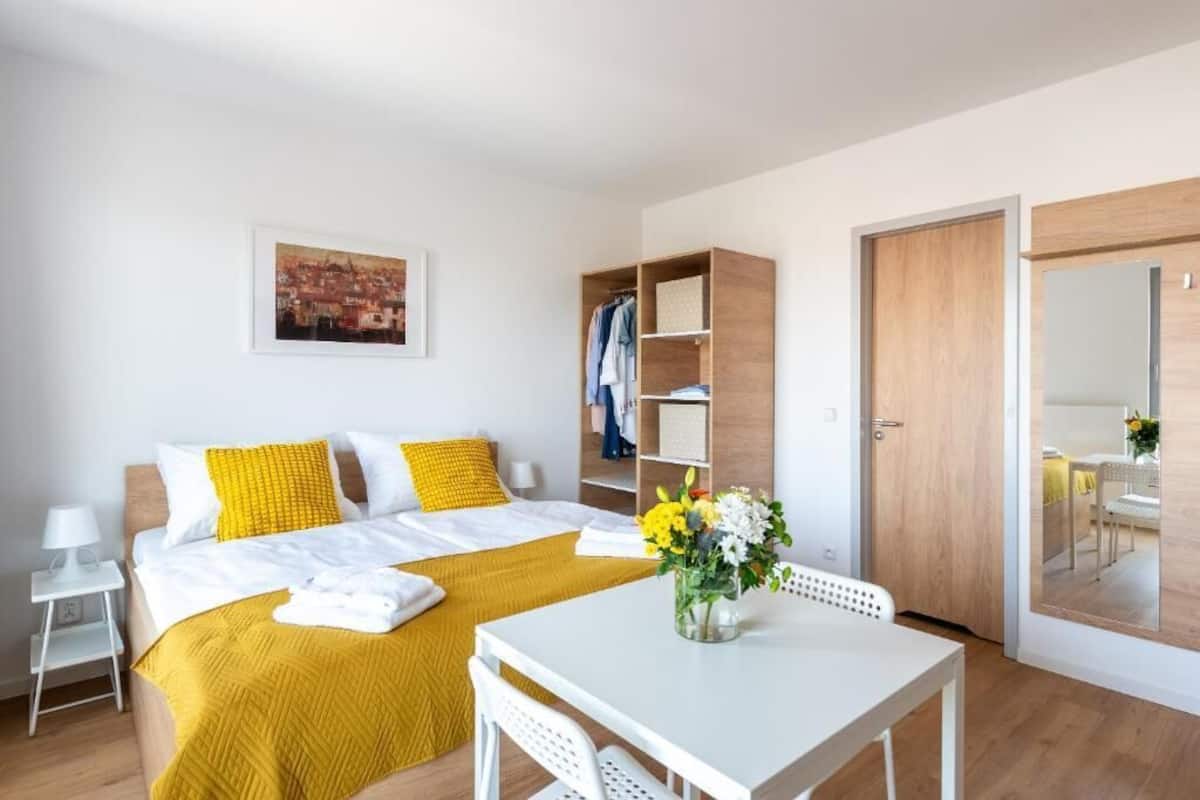 Une chambre d’hôtel avec un lit, une table, une chaise, une armoire, un miroir et un tableau au mur.
