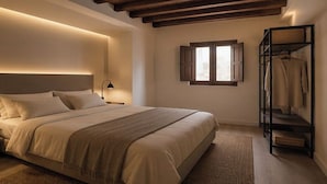 A bedroom with a bed, bedside lamp, wooden beams, a window, and a clothing rack. - Magnolia Suites by Blossom Hotels (Granada)
