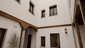 Une cour avec une fontaine, des plantes en pot et un bâtiment doté de nombreuses fenêtres et de balcons.