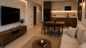 Un salon moderne doté d’un téléviseur à écran plat, d’une table basse en bois, d’un canapé et d’un coin repas avec une table et des chaises.