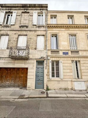 Un immeuble de deux étages avec une porte en bois, un balcon orné de balustrades en fer forgé et une enseigne indiquant « RUE FERNAND MARIN ».