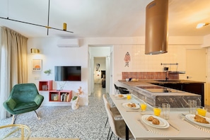 Eine moderne Küche mit Marmorarbeitsplatte, einer Edelstahl-Dunstabzugshaube und einer Frühstücksecke mit Croissants und Orangensaft.
