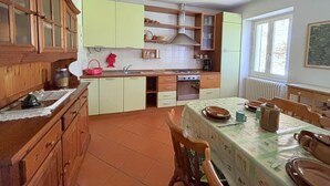 Una cocina con armarios de madera, una mesa de comedor con platos y una tetera, y un ventanal con vistas.