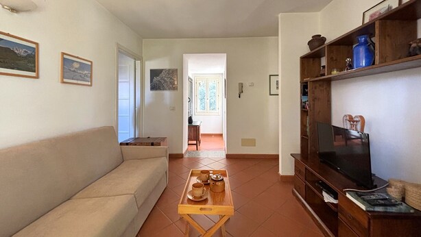 Una sala de estar con un sofá, una mesa de centro con tazas, un televisor y una estantería.