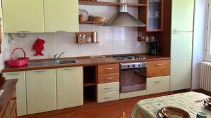 Una cocina con armarios de tonos claros, una estufa a gas, horno empotrado y campana extractora de acero inoxidable.
