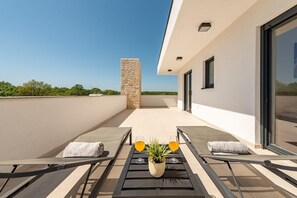 A rooftop terrace with sun loungers, a potted plant, and two glasses of orange juice. - Villa Antonio Zadarvillas (Nin)