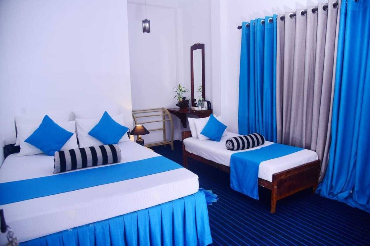 A hotel room with two beds, a nightstand, a mirror, and a window with curtains.