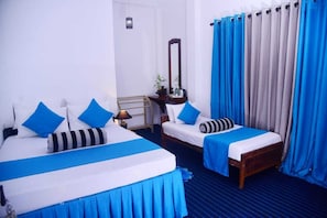 Quarto de hotel com duas camas, mesa de cabeceira, espelho e janela com cortinas.