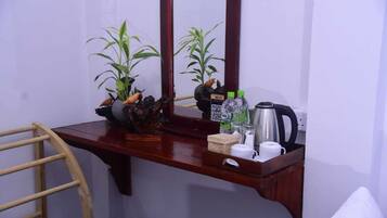 Un escritorio de madera con un espejo, dos plantas en macetas, una tetera, una cafetera y un cartel de Wi-Fi.
