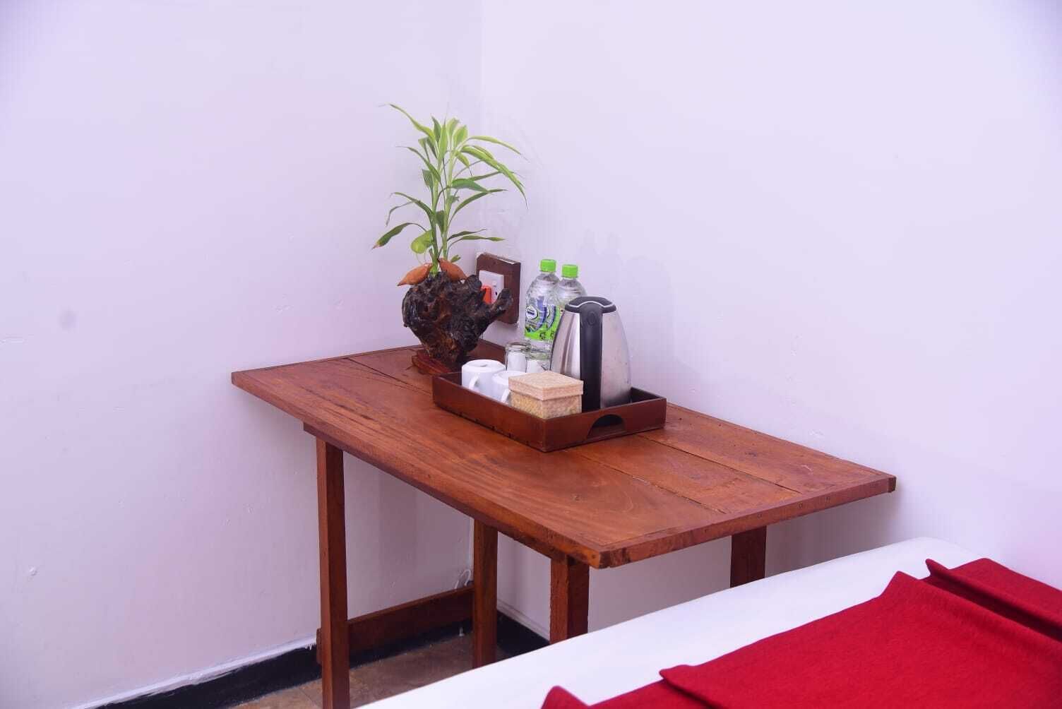 Une petite table en bois, sur laquelle se trouvent une plante, une machine à café et un plateau avec divers objets.