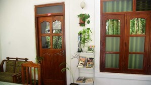 A room with a wooden door, a bookshelf with books, a small table, and a chair. - Travel Rest Inn (Ella)