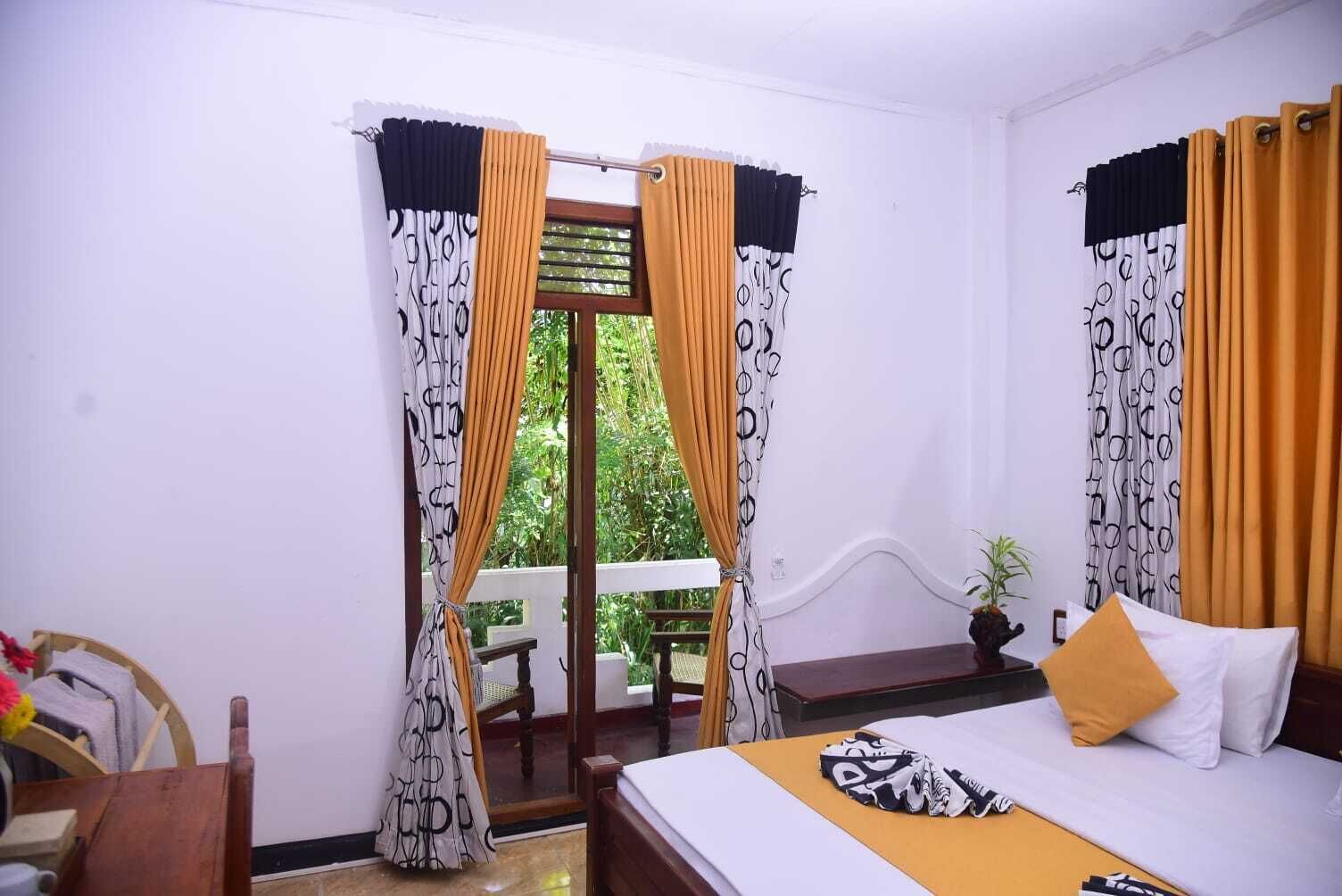 A bedroom with a bed, a window with curtains, a chair, and a small table.