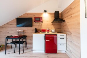 Une cuisine compacte équipée d’un four à micro-ondes, d’un grille-pain et d’un lave-vaisselle rouge.