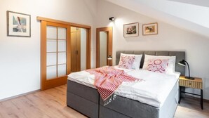 Un dormitorio con cama, mesita de noche, lámpara, armario y dos cuadros en la pared.