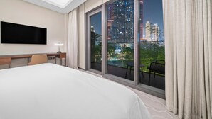 A hotel room with a large bed, a desk, a chair, a TV, and a balcony with a city view. - 2BR Address Residences Dubai Opera, Burj Khalifa View from all the rooms (Dubai)