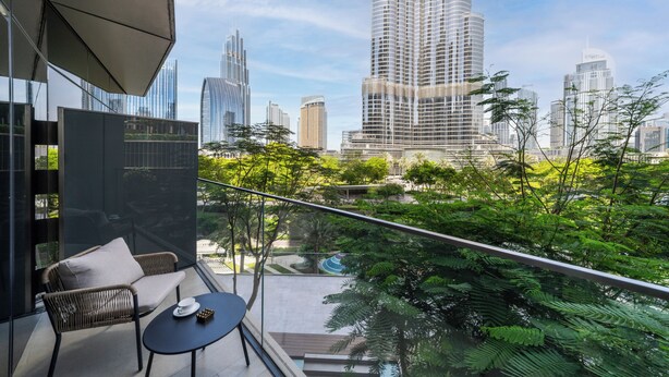 A balcony with a view of a cityscape, including tall buildings and greenery. - 2BR Address Residences Dubai Opera, Burj Khalifa View from all the rooms (Dubai)