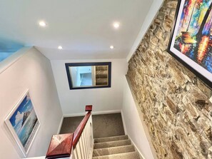 A staircase with a stone wall, a framed picture, and a ceiling with recessed lighting. - Hydrangea Cottage (St Austell)