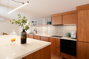 A modern kitchen with wooden cabinets, a white countertop, a black dishwasher, and a green coffee maker. - Luxury-3-bedroom Apartment with Private Rooftop Terrace, Sauna,Hot Tub in Pärnu (Pärnu)