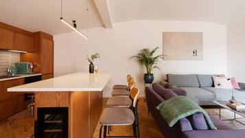 A modern kitchen with a central island, wooden cabinets, and a dining area with a sofa and chairs.