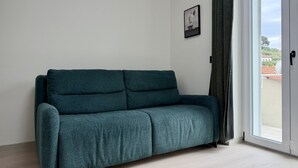 Un canapé de couleur turquoise dans une pièce dotée d’une grande fenêtre et d’une porte.
