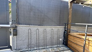 Une terrasse dallée de pierres, avec une clôture en métal et un portail en bois.