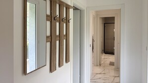 A hallway with a wooden panel wall, a large mirror, and a door leading to a room with a tiled floor. - Dimora degli Ulivi C (Imperia)