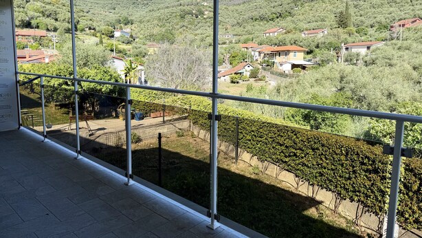 A balcony with a view of a hillside with houses and greenery. - Dimora degli Ulivi C (Imperia)