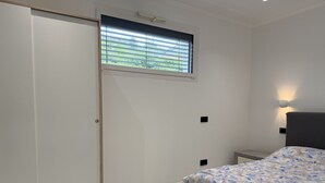 A bedroom with a bed, a wardrobe, a window, and a nightstand. - Dimora degli Ulivi C (Imperia)