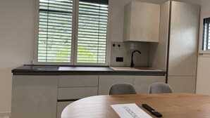 A modern kitchen with a window, a sink, and a wooden table with a remote control and a paper. - Dimora degli Ulivi C (Imperia)