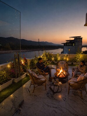 Una terraza con sillones de mimbre, un hogar y plantas en macetas.