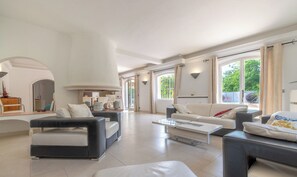 Ein geräumiges Wohnzimmer mit modernem Design, ausgestattet mit einer großen Couch, einem Couchtisch und einem Essbereich mit einer Küche im Hintergrund.