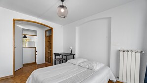 A bedroom with a bed, a desk, a chair, a radiator, and a wardrobe. - Superb Apartment with Panoramic View – Sleeps 8 – Marseille 9th District (Marseille)