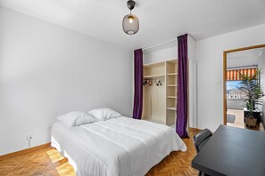 Ein Schlafzimmer mit Bett, Schreibtisch, Stuhl, Kleiderschrank und einer Topfpflanze.