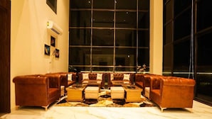 A spacious living area with a large window, leather sofas, a coffee table, and a marble floor.