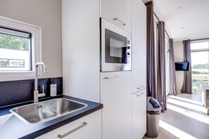 A modern kitchen with a built-in microwave, a sink, and a window. - Cube XL 72 | 4 persoons chalet in Zennewijnen (Zennewijnen)