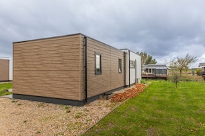 Ein modernes, mobiles Haus mit flachem Dach, großen Fenstern und einer Zuwegung mit Kies.