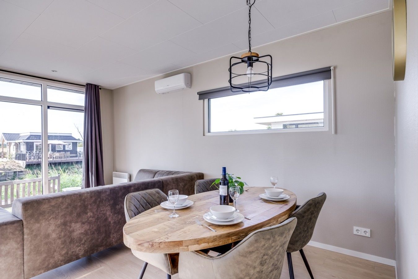 A dining area with a wooden table set for two, a bench, and a view of the outdoors.