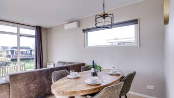 A dining area with a wooden table set for two, a bench, and a view of the outdoors.